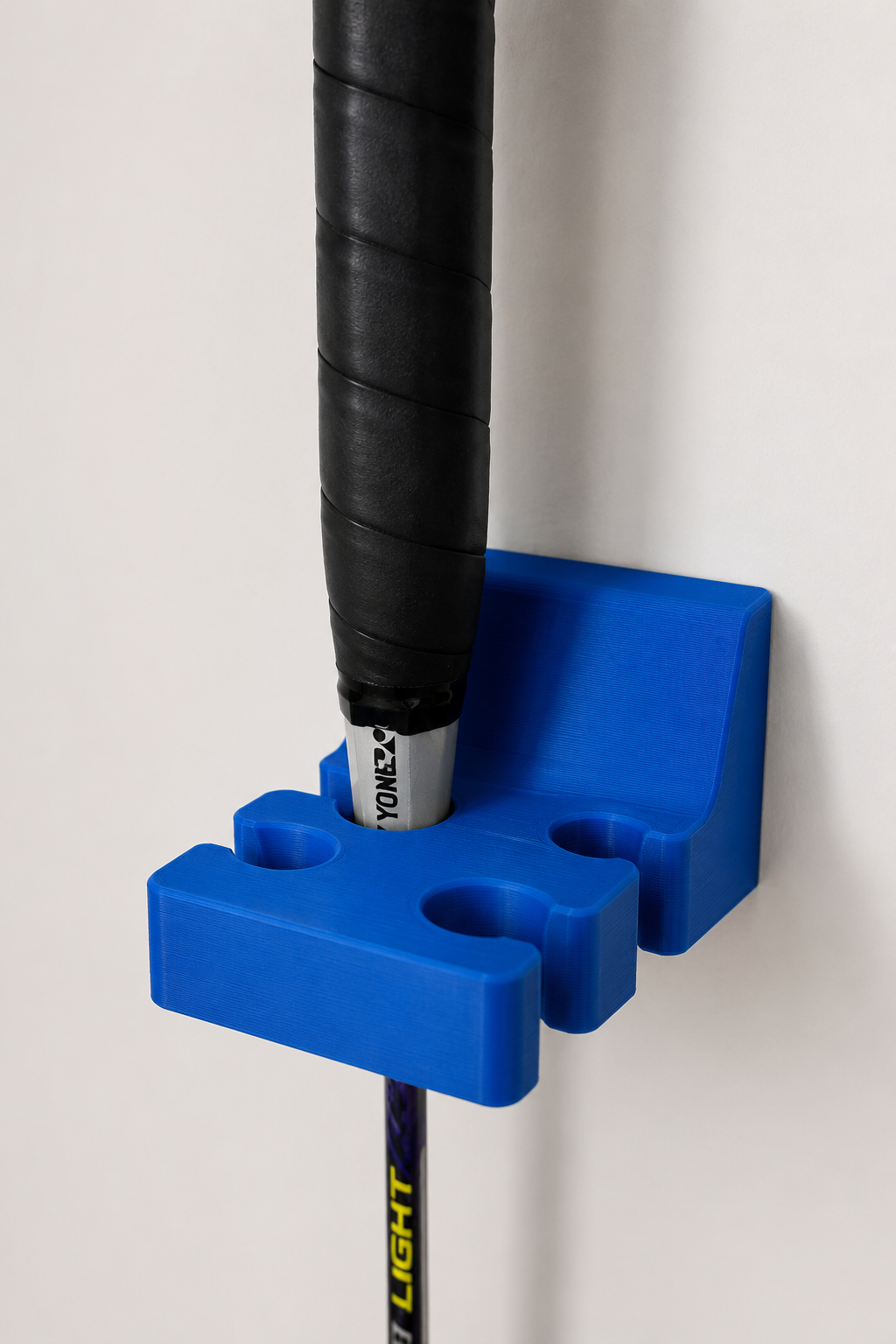 Blue Wall Mount Badminton Racket Holder made from PLA holding a badminton racket on a wall.