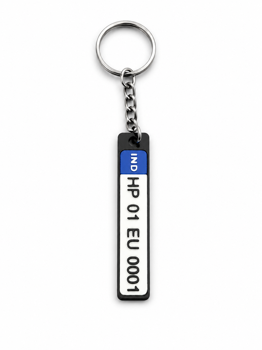A novelty keychain featuring a vertical license plate-shaped charm with a black top section, a blue 'IND' tab, and a white plate area printed with 'HP 01 EU 0001' in black text, attached to a silver metal ring and chain on a white background.